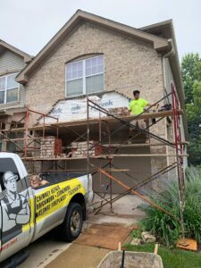 Adv Masonry worker performing brick restoration Naperville on residential garage wall with matching brick replacement