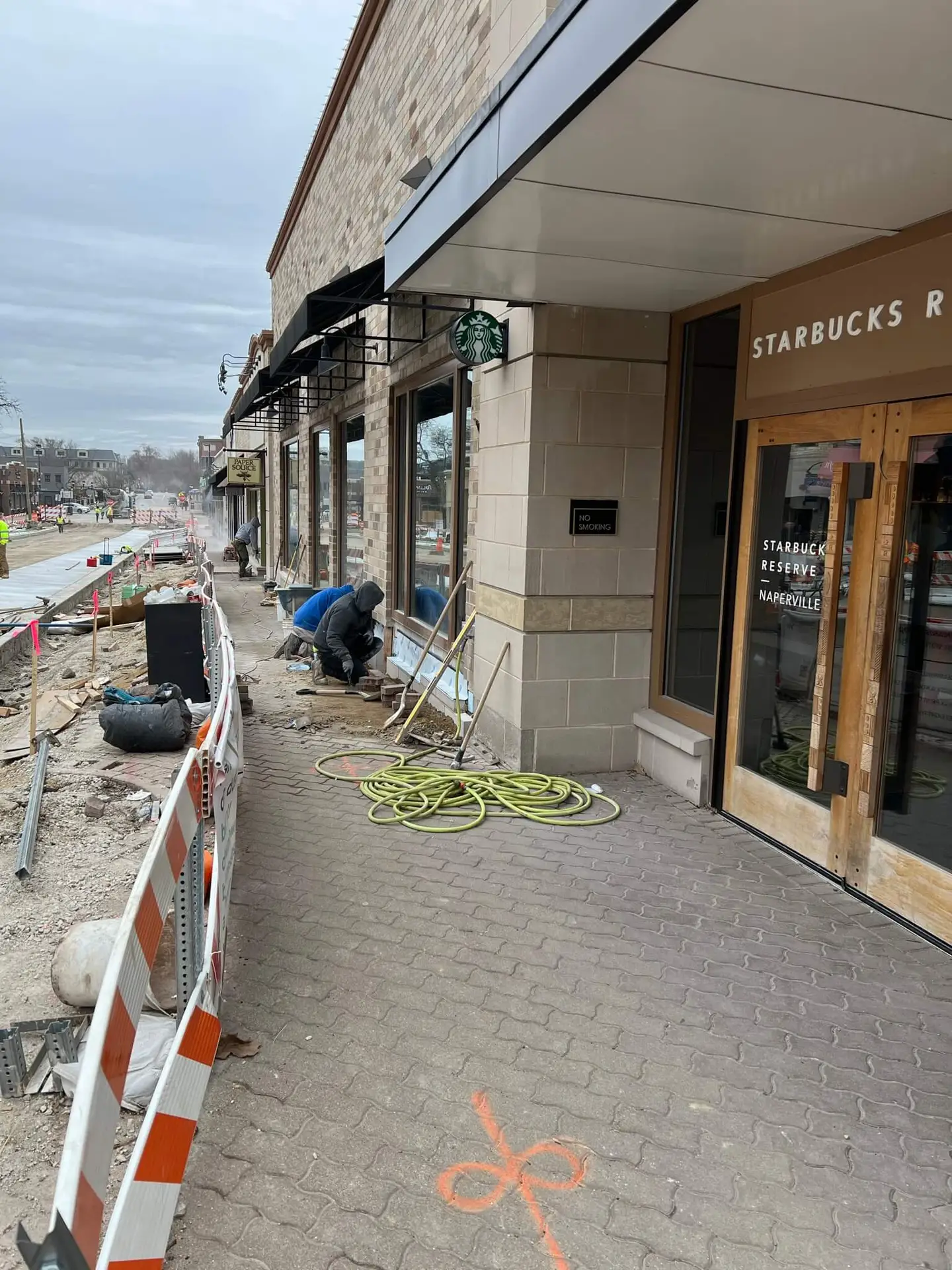 Adv Masonry worker performing Naperville brick repair on Starbucks building exterior during commercial brick wall restoration