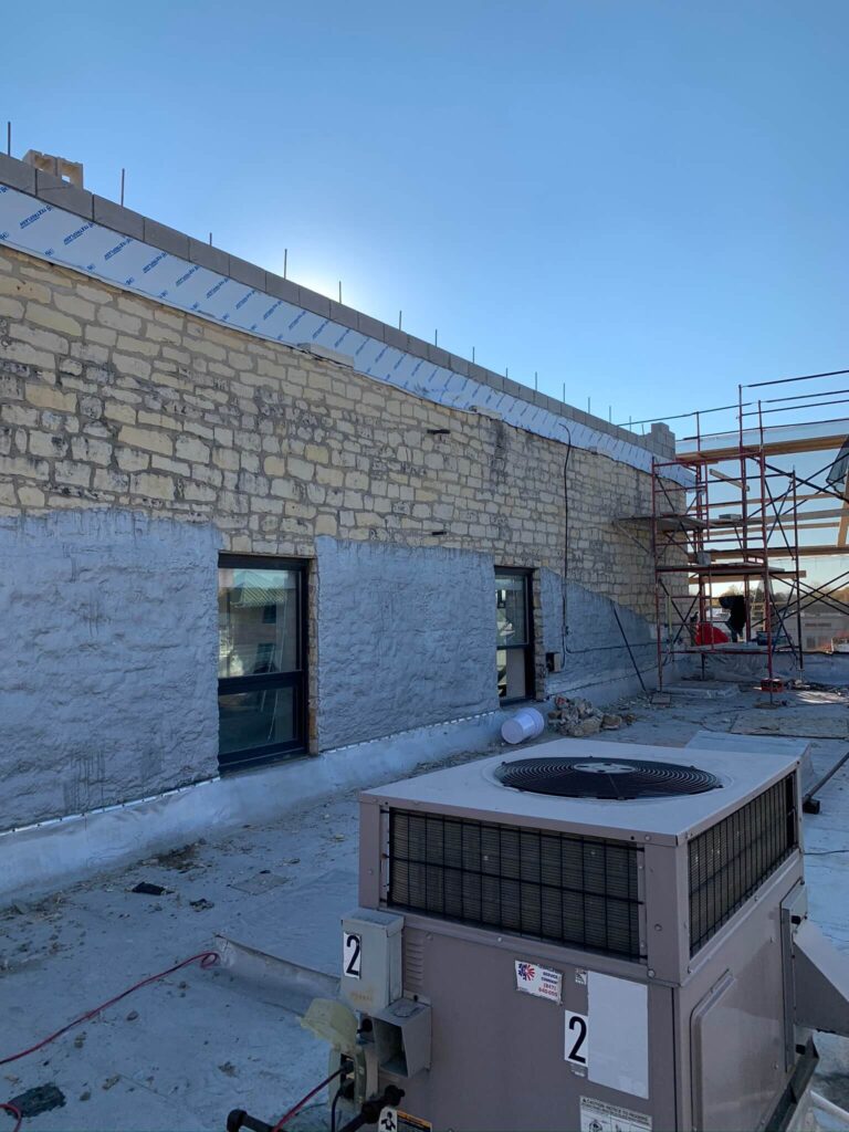 Adv Masonry performing Naperville brick repair and waterproofing on exterior brick wall of high-rise building