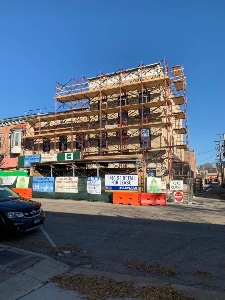 Adv Masonry performing brick repair Naperville on historic downtown building with scaffolding in place